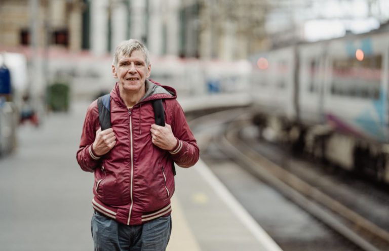 Man standing on train station platform with rucksack on back