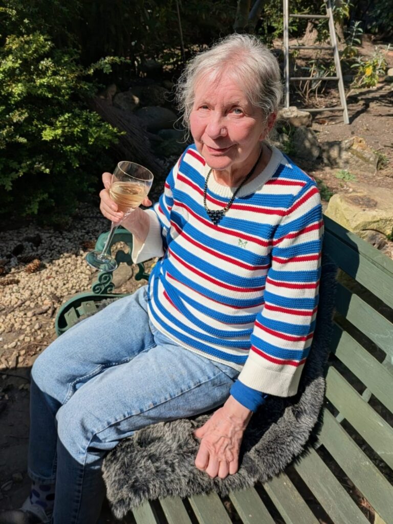 Image of Dorothy on a bench drinking a glass of wine.