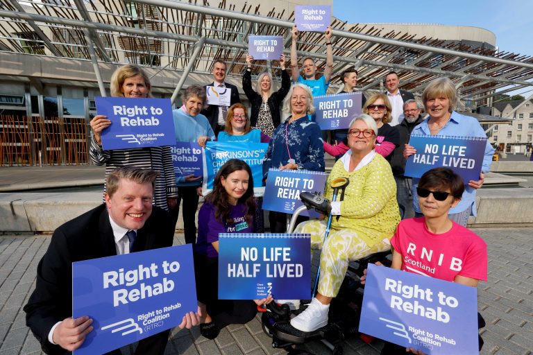 A photo of a group of people holding 'Right to Rehab' signs.