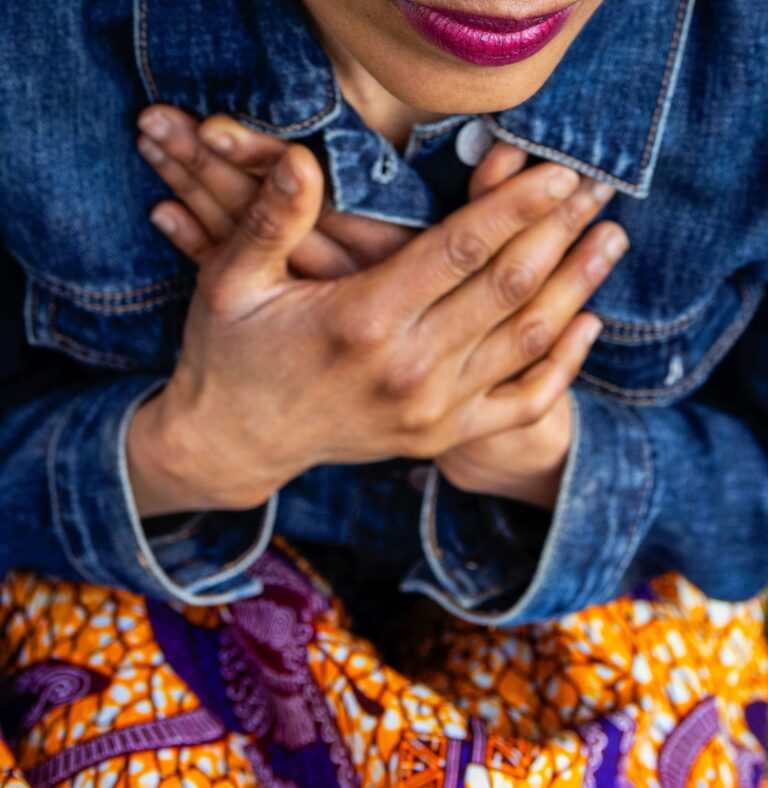 Photograph of a woman with her hands crossed against her chest.